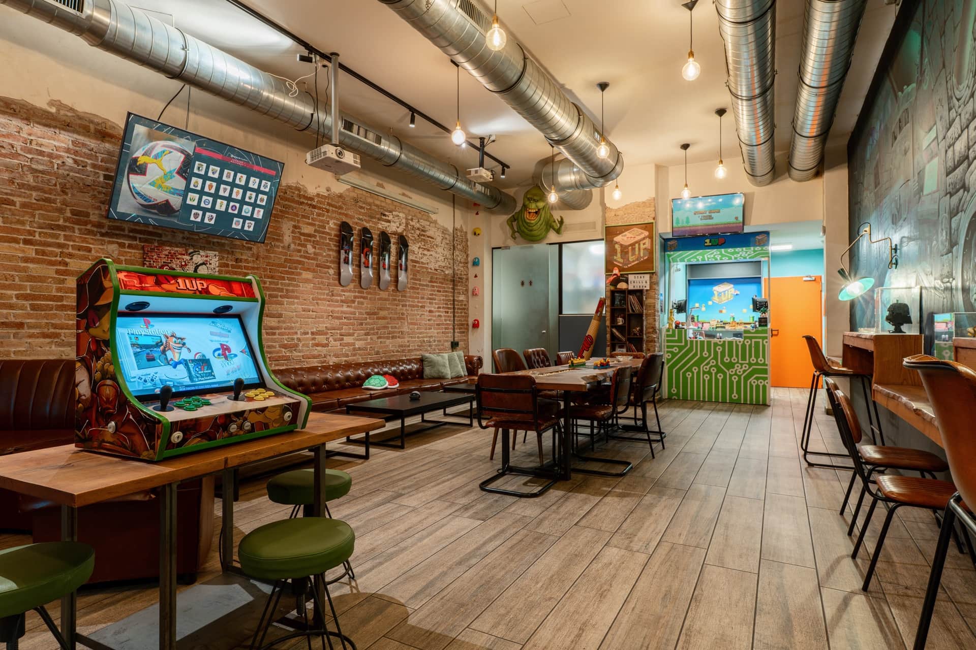Zona lounge con cabinato arcade nel social club 1UP Barcellona